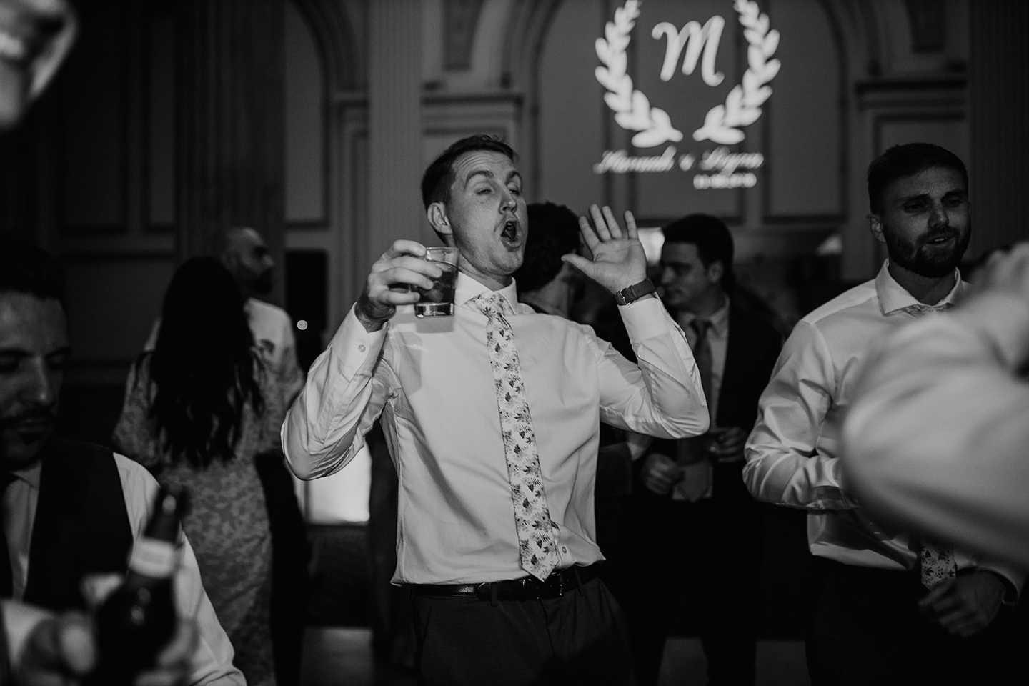Guests dancing at an indoor event with decorative monogram