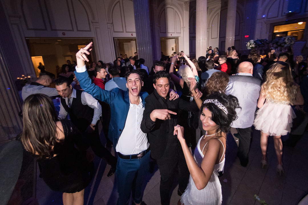 Guests dancing at an elegant venue with purple lighting